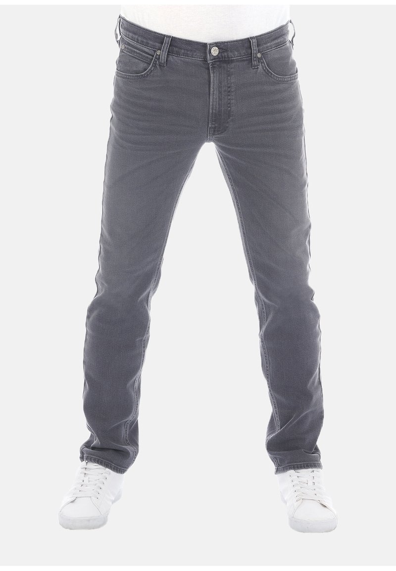 Jeans de mezclilla gris con corte ajustado, estilo de cinco bolsillos y detalles de desgastado ligero. Combinados con zapatillas blancas. Parte delantera plana y diseño clásico.