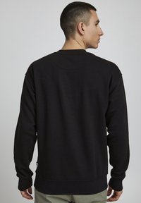 Zwarte sweatshirt met een relaxte pasvorm, ronde hals en geribde cuffs. Zachte textuur en minimalistisch ontwerp, voorzien van een discreet logo aan de zoom.