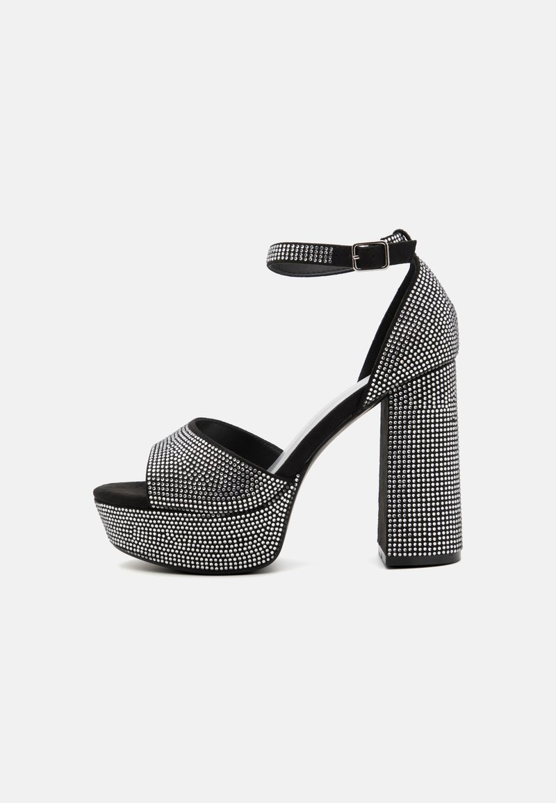 Črne platform sandale z obliko okrašenjo z rhinestones, ki imajo zaobljen prst, trak za gleženj in debel visok pet.