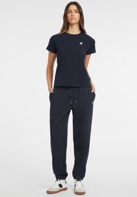 Navy cotton t-shirt with short sleeves and a small logo on the chest, paired with matching navy sweatpants featuring side pockets and a drawstring.
