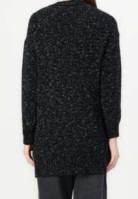 Stickad tröja i svart och vitt, med en texturerad yta, långa ärmar och en ribbad nederkant, med en avslappnad passform och medellängd.