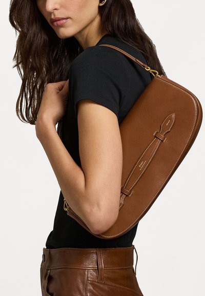 Brūna ādas pleca soma ar elegantu, izliekta formu, dodoties ar vienu siksnu un smalkiem dūriena akcentiem. Gluda tekstūra.