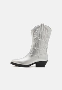 Botas vaqueras de cuero plateado con puntera puntiaguda, tacón bajo, costuras decorativas y lengüeta. Textura suave con un acabado brillante.