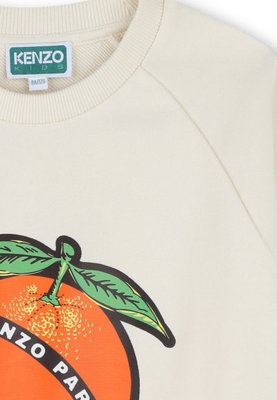 Sweatshirt de couleur crème avec un grand graphique orange et des feuilles vertes. Présente des bordures côtelées au niveau du col et des épaules, en matériau coton doux.