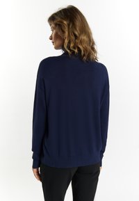 Marineblauer Strickpullover mit gerippten Bündchen und Saum. Lockerer Schnitt mit Polo-Kragen und einer strukturierten Oberflächenverarbeitung.