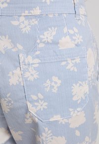 Lichtblauwe stoffen shorts met witte bloemmotieven en dunne blauwe strepen. Voorzien van een achterzak en subtiele stikseldetails.