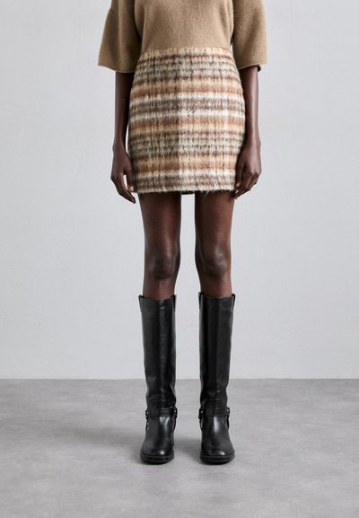 Wollen blend rok met een bruin en beige geruit patroon, gecombineerd met kniehoge zwarte leren laarzen met gespen.