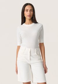White ribbed sweater with short sleeves, paired with white denim shorts. Both garments feature a smooth texture and minimalist design.