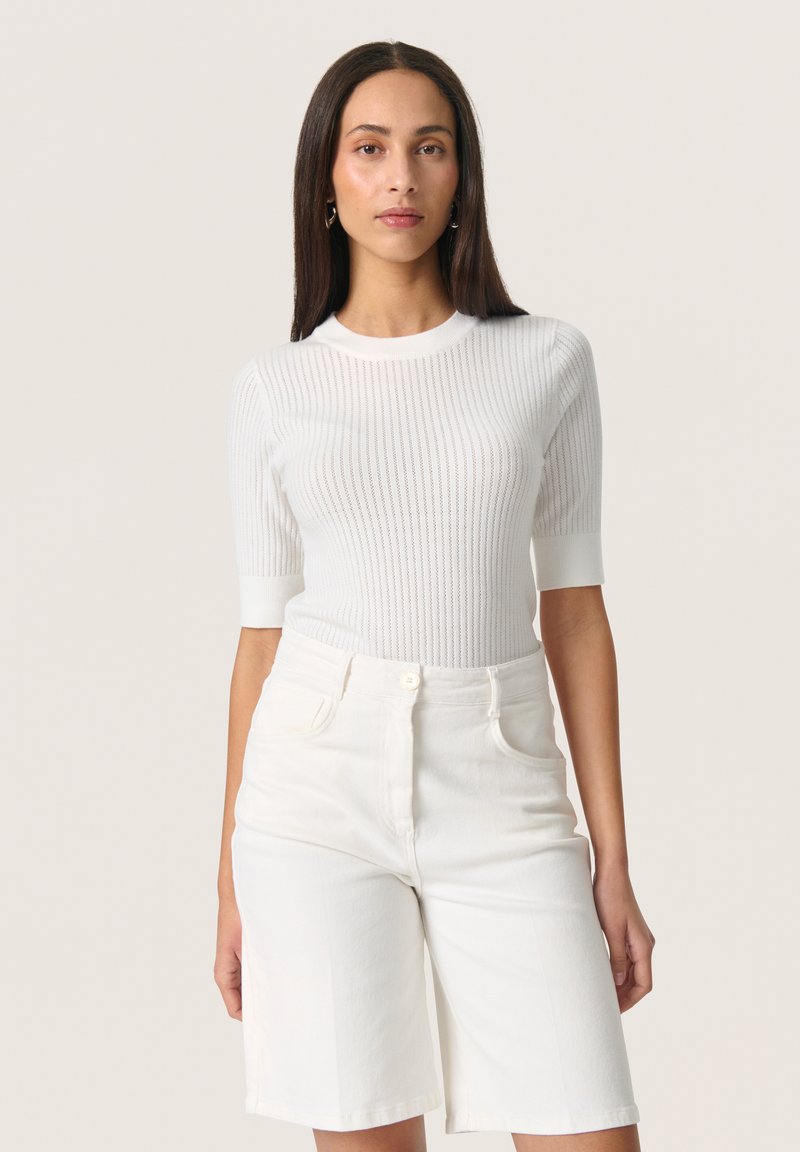 White ribbed sweater with short sleeves, paired with white denim shorts. Both garments feature a smooth texture and minimalist design.