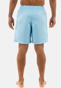 Pantaloni da mare azzurro chiaro realizzati in tessuto leggero, dotati di vita elastica e di un taglio dritto, visti da dietro.