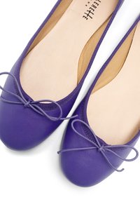 Ballerine viola realizzate in materiale sintetico liscio, con punta tonda e un'opzione testurizzata vicino al fiocco. Utilizzo suggerito per interni.