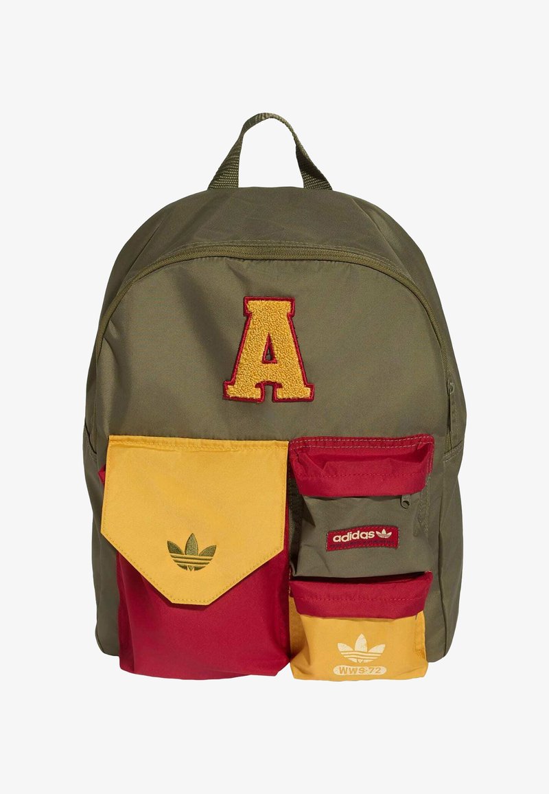 Mochila verde con gran letra A amarilla, bolsillos delanteros rojos y amarillos con logos de Adidas y detalles rojos en la cremallera.
