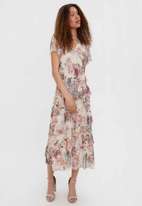Kwiatowa sukienka maxi z lekkiego materiału z falbanami. Ozdobiona pastelowymi różowymi i fioletowymi kwiatami, z krótkimi rękawami i dekoltem w serek.