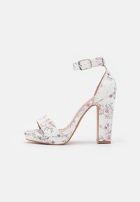 Sandal con tacco alto a piattaforma bianca con punta aperta, cinturino alla caviglia e tacco a blocco; presenta motivi floreali rosa e verdi su tessuto.