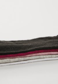 Cinque calzini impilati di vari colori: nero, rosso scuro, rosa chiaro, grigio e bianco, realizzati in un materiale morbido con una texture liscia.