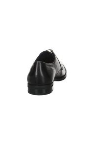 Chaussure habillée en cuir noir avec une texture lisse, un bout arrondi, un petit talon et un détail de couture le long des côtés.