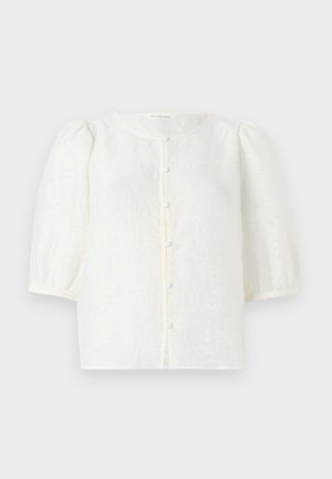 Blusa branca com tecido texturizado, decote redondo e mangas curtas bufantes. Apresenta um fecho frontal com pequenos botões redondos.