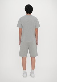 Grå bomulls t-skjorte med korte ermer og rund hals, kombinert med matchende grå shorts. Minimalistisk design, avslappet passform og myk tekstur.