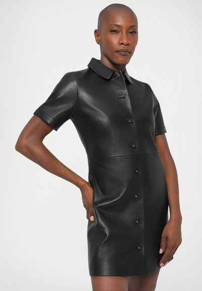 Czarna skórzana sukienka koszulowa z kołnierzykiem, krótkimi rękawami i zapięciem na guziki z przodu. Gładka tekstura, dopasowany krój, długość do kolan.