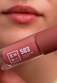 Olio labbra in un tubo trasparente con un cappuccio opaco di colore rosa soft. L'etichetta mostra "503" e "THE COLOR LIP OIL" in lettere bianche.