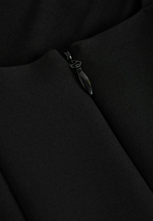 Black fabric with a smooth texture featuring an exposed zipper and a pointed pull tab, partially visible on the garment's seam.