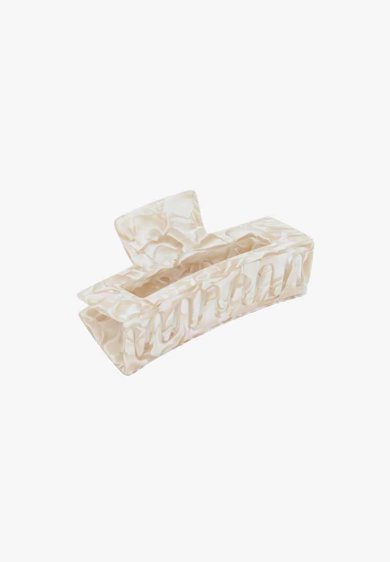 Hårklipp i marmorerad gräddfärgad plast, rektangulär form med en rundad bas, med utskurna sektioner och en flat topp för grepp.