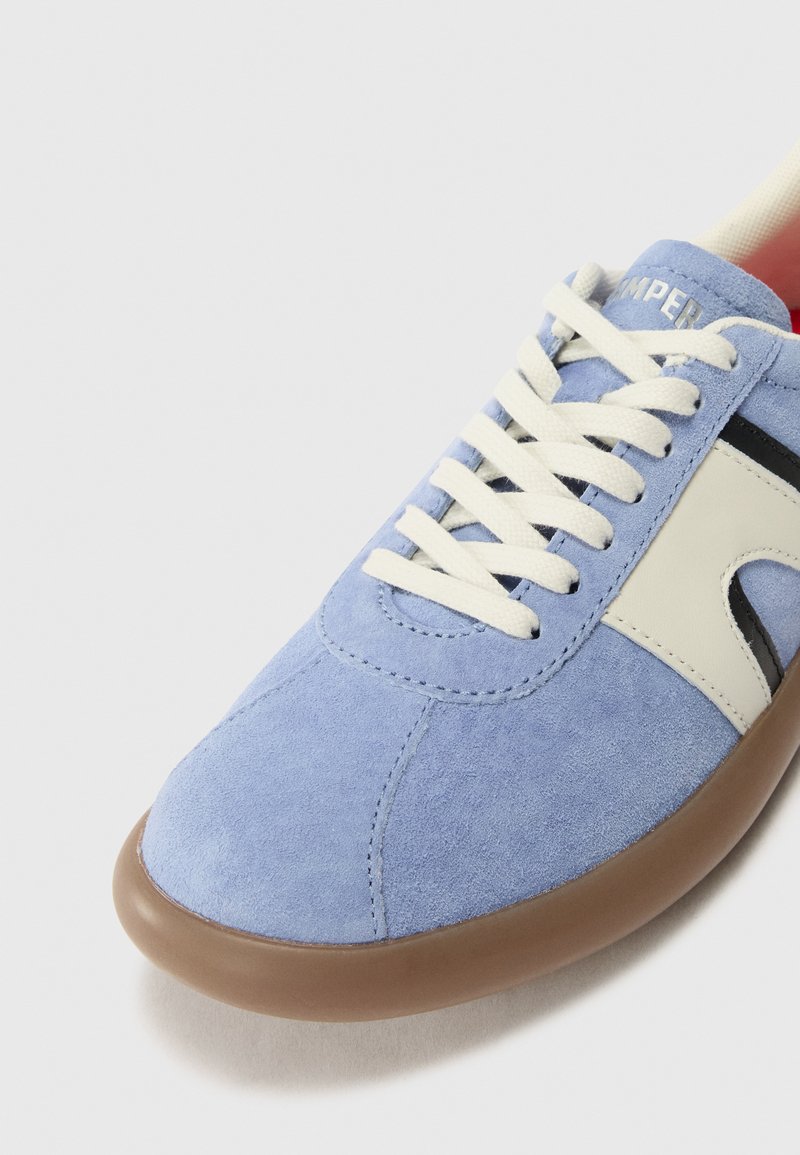 Zapatillas de ante azul con detalles en crema, puntera redondeada y cordones blancos. Presentan una suela de goma marrón y un logotipo sutil en la lengüeta.