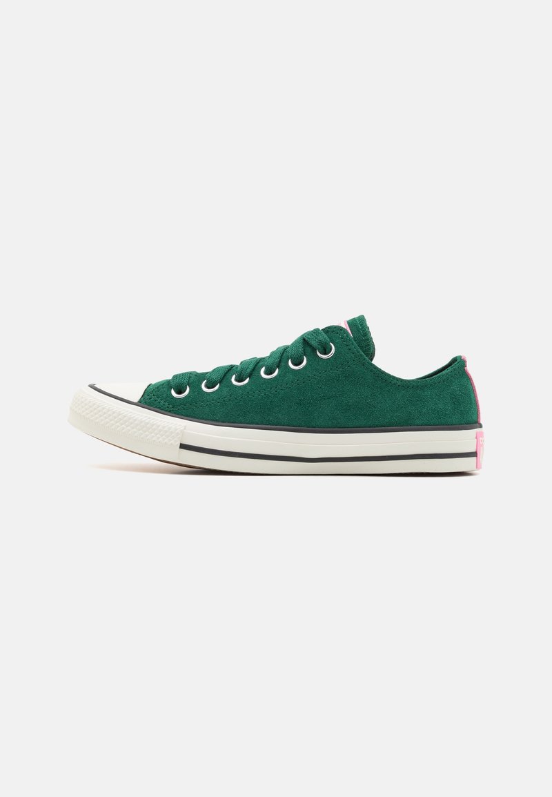 Baskets basses avec dessus en daim vert, semelle en caoutchouc blanche avec une bande noire et des accents roses au talon et à la languette.