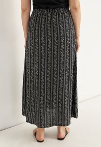 Maxikleid mit floralen Mustern in Schwarz und Weiß, mit vertikalen Streifen, elastischem Bund und seitlichem Schlitz. Aus weichem, leichtem Stoff.