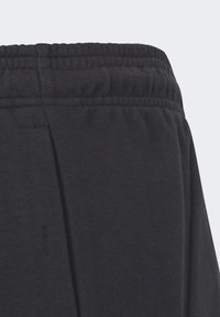 Pantalones de chándal de algodón negros con cintura elástica acanalada, textura suave y detalle en la costura lateral, diseñados para la comodidad y facilidad de uso.