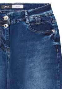 Pantalon en denim bleu foncé à la texture lisse, avec deux boutons-pression brillants et une poche avant; étiqueté "CECIL DENIM."