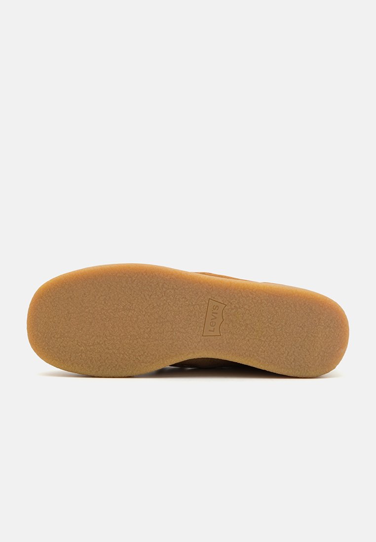 Semelle en caoutchouc marron avec une surface texturée, arborant un logo Levis bien visible. Le design est plat avec des bords légèrement surélevés.