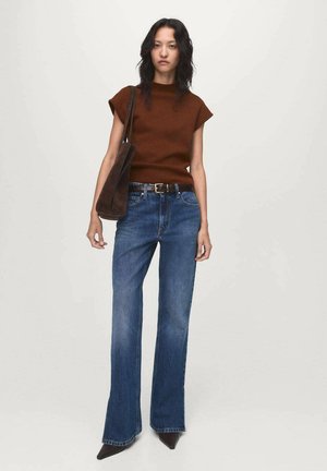 Brown short-sleeve sweater, high-waisted blue flared jeans, and a dark brown shoulder bag. The jeans have a faded texture and bootcut design.