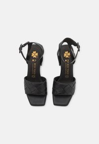 Schwarze Leder-Sandalen mit einem geflochtenen Riemendesign, quadratischer Zehenpartie, verstellbarem Knöchelriemen und niedrigem Blockabsatz.
