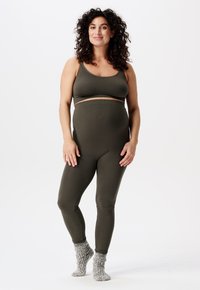 Olijfgroene geribbelde bralette en legging-set, met een aansluitend ontwerp en een elastische tailleband. Model draagt gezellige gebreide sokken.