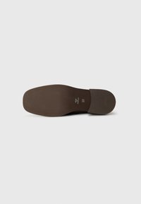 Semelle de chaussure marron avec un motif texturé et une légère voûte. Les détails comprennent une taille et un logo en relief. Finition lisse avec une forme arrondie.