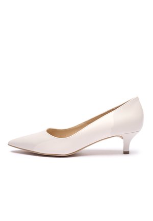 Biały lakierowany czółenko z zaostrzonym noskiem, niskim obcasem i gładką powierzchnią. Wnętrze posiada prosty, zaokrąglony otwór.