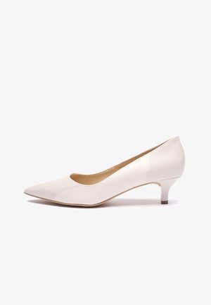 Biały lakierowany czółenko z zaostrzonym noskiem, niskim obcasem i gładką powierzchnią. Wnętrze posiada prosty, zaokrąglony otwór.