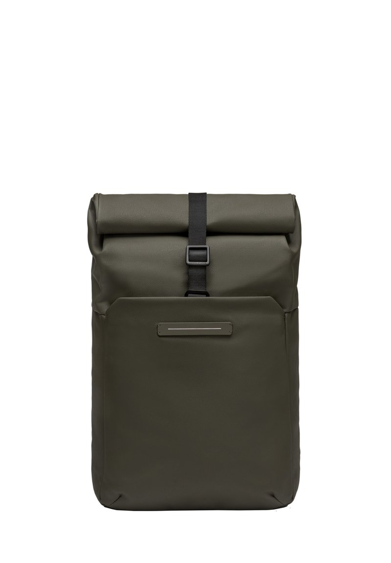 Sac à dos à rabat en vert olive, fabriqué à partir de matériau imperméable. Il dispose d'une sangle noire avec une boucle et d'une poche avant avec un accent argenté.