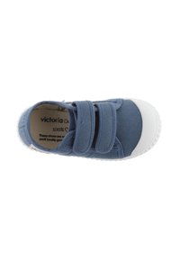 Scarpa di tela blu con due strappi in velcro, punta in gomma bianca, suola testurizzata e etichetta interna che mostra il nome del marchio e le informazioni sui materiali.
