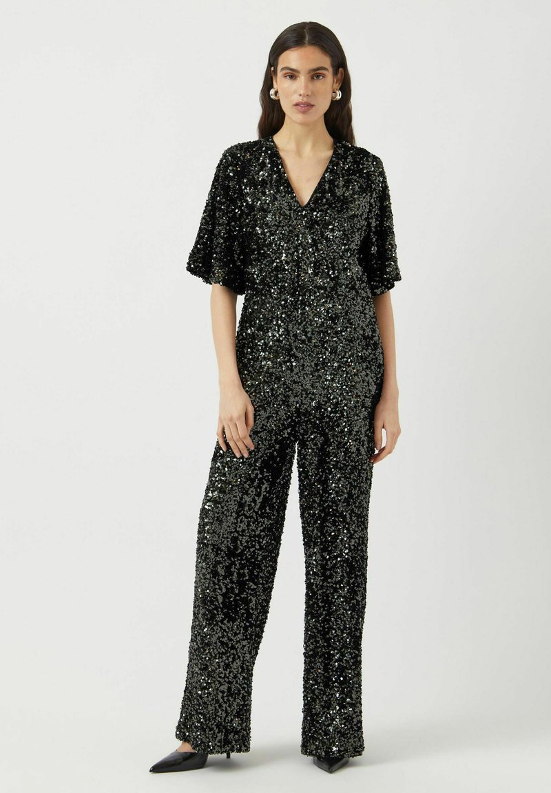 Tuta intera nera con paillettes, maniche corte, scollo a V, vestibilità rilassata e gambe larghe. Presenta paillettes lucenti e testurizzate su tutta la superficie.