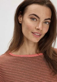 Braun gestreiftes Langarmshirt mit pinken Akzenten und weitem Ausschnitt, gefertigt aus einem leichten, leicht durchscheinenden Material.