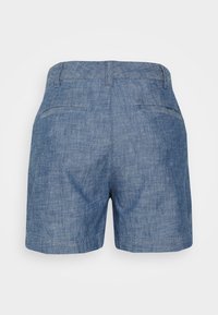 Vaaleansiniset farkkushortsit, joissa on teksturoitu viimeistely. Niissä on sileä vyötärönauha ja kaksi takataskua, joissa on hienovaraiset saumakoristeet.