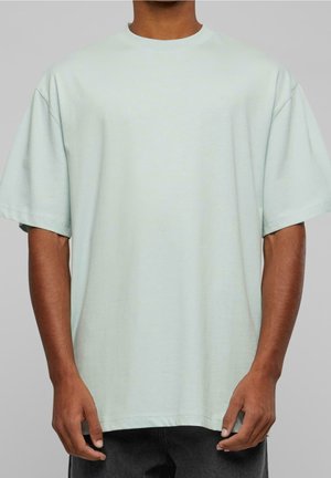 Lysegrøn oversized t-shirt, korte ærmer, rund halsudskæring, blød bomuldstekstur, lige kant, båret med mørke jeans, minimal detaljer.