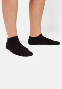 Svarta ankelsockor i mjukt material, med en slät yta, minimalistisk design och utan synliga mönster eller logotyper.