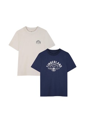Due magliette Timberland a maniche corte con scollo rotondo; una beige con piccolo logo, una blu navy con grande logo bianco e testo sul davanti.