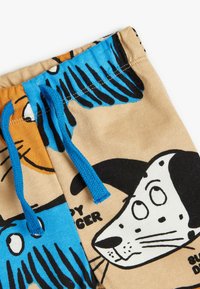 Brune stofshorts med et legende hundehovede-tryk, blå snor og sorte detaljer samt en glat tekstur.