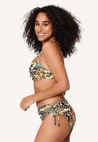 Conjunto de bikini con un estampado colorido de mariposas en amarillo, naranja y negro, con lazos ajustables en la parte inferior y un diseño de top que ofrece soporte.