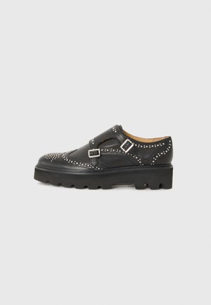 Scarpe in pelle nera con dettagli borchiati, cinturini a doppia fibbia e suola spessa. Presentano un motivo decorativo nella zona delle punte.