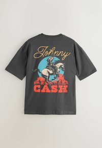 Szürke rövid ujjú póló, amelyen egy színes grafika látható egy cowboyról lóháton, a "Johnny CASH" szöveg vastag piros és arany betűkkel.